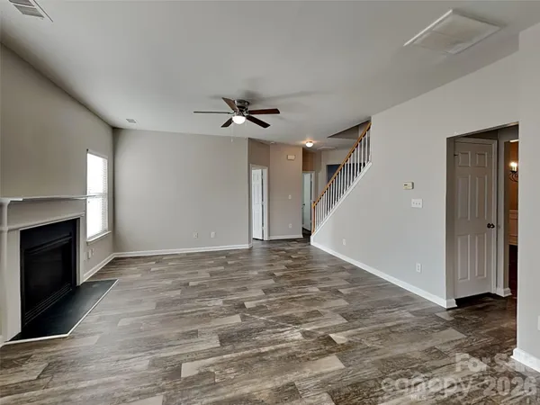 a view of a livingroom with a fireplace a ceiling fan and wooden floor