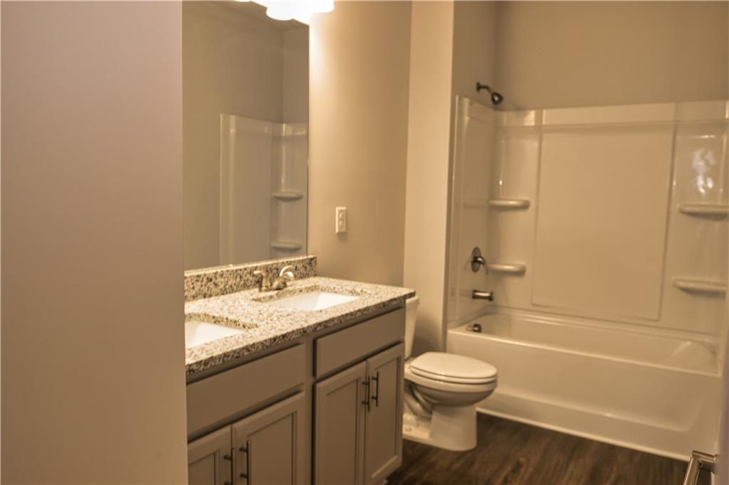 6120 Ripple Way, Unit 46 Atlanta, GA 30349 - Photo 18 of 19 a bathroom with a granite countertop toilet a sink and a bathtub