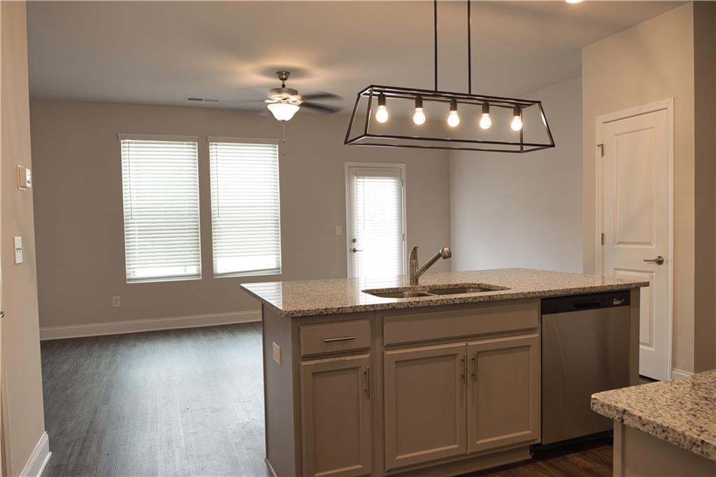 6120 Ripple Way, Unit 46 Atlanta, GA 30349 - Photo 3 of 19 a kitchen with stainless steel appliances granite countertop a sink dishwasher a stove and a dining table with wooden floor