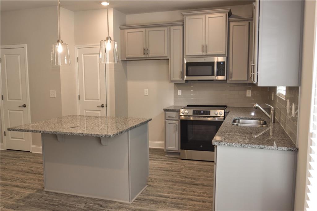 6120 Ripple Way, Unit 46 Atlanta, GA 30349 - Photo 5 of 19 a kitchen with stainless steel appliances granite countertop a stove a sink and a microwave