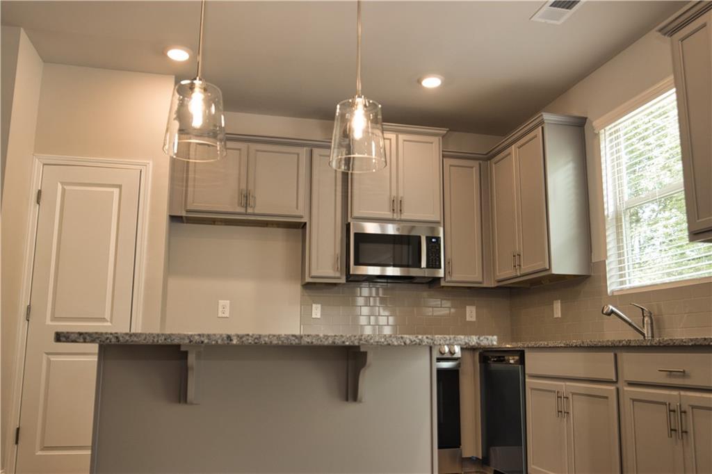6120 Ripple Way, Unit 46 Atlanta, GA 30349 - Photo 6 of 19 a kitchen with stainless steel appliances granite countertop a sink a stove and a microwave