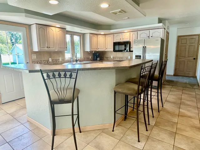 a kitchen with stainless steel appliances granite countertop a stove a refrigerator a microwave oven with a dining table and chairs