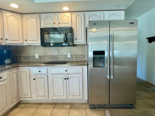 a kitchen with stainless steel appliances granite countertop a refrigerator a stove and a sink