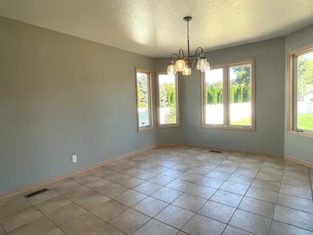 a view of an empty room with windows and chandelier