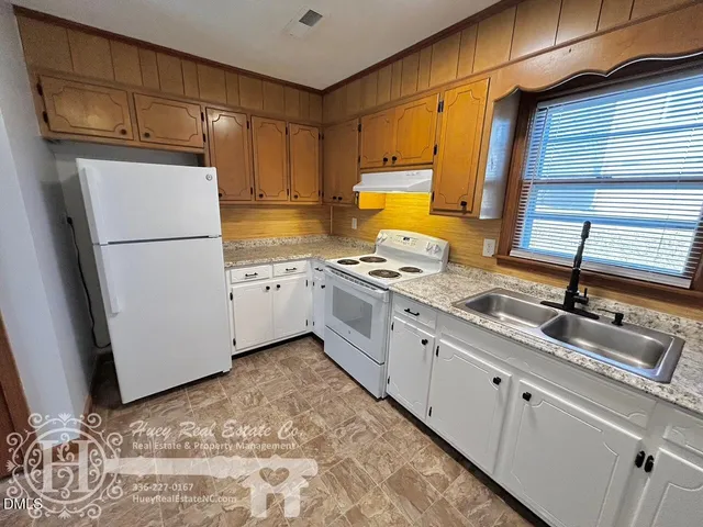 a kitchen with granite countertop a refrigerator sink stove and cabinets