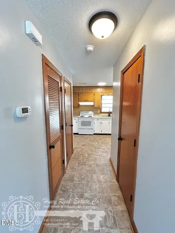 a view of a hallway with wooden floor and a bathroom