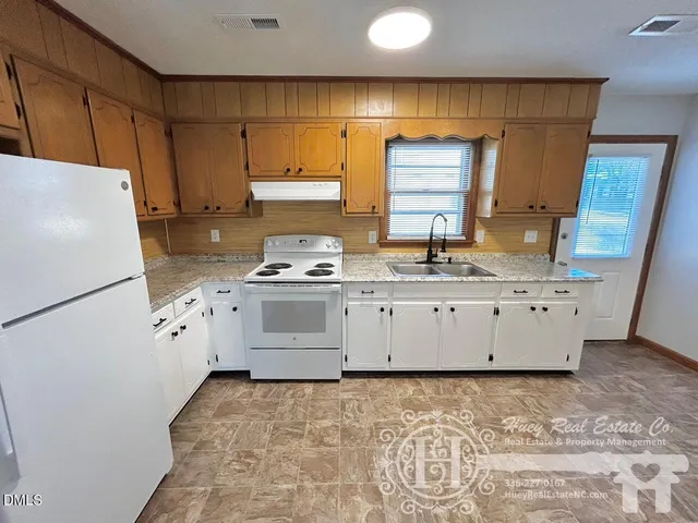 a kitchen with granite countertop a sink a stove a refrigerator and cabinets