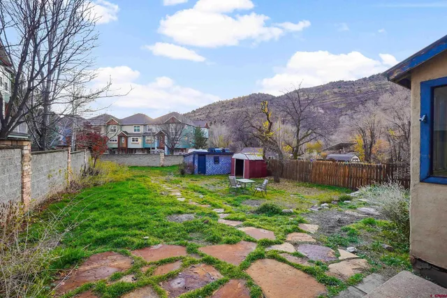 a sign that is sitting in front of a house with a big yard