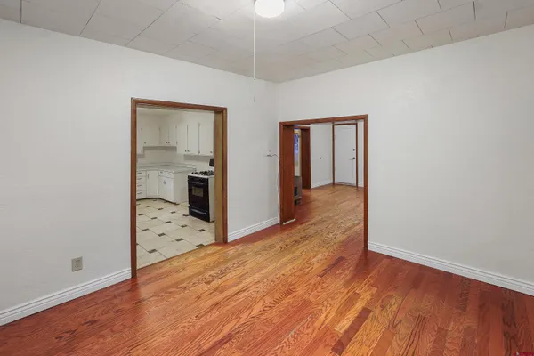an empty room with wooden floor and bathroom view