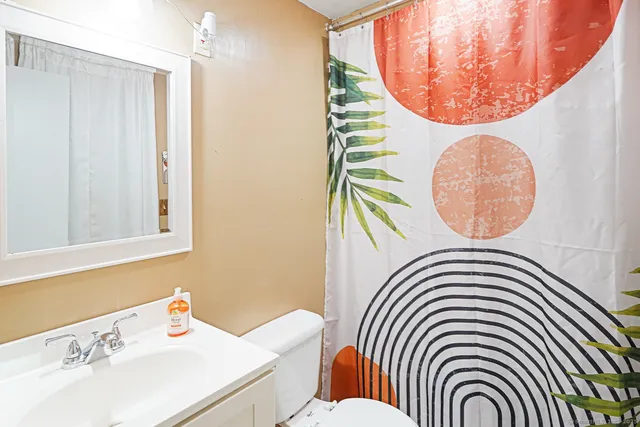 a bathroom with a sink a mirror and a shower curtain