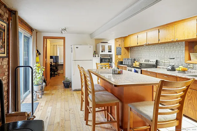 a dining hall with stainless steel appliances kitchen island granite countertop a table chairs and a refrigerator