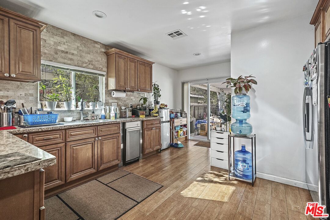 1945 Summit Avenue Pasadena, CA 91103 - Photo 7 of 15 a kitchen with stainless steel appliances granite countertop a refrigerator oven a sink dishwasher and white cabinets with wooden floor