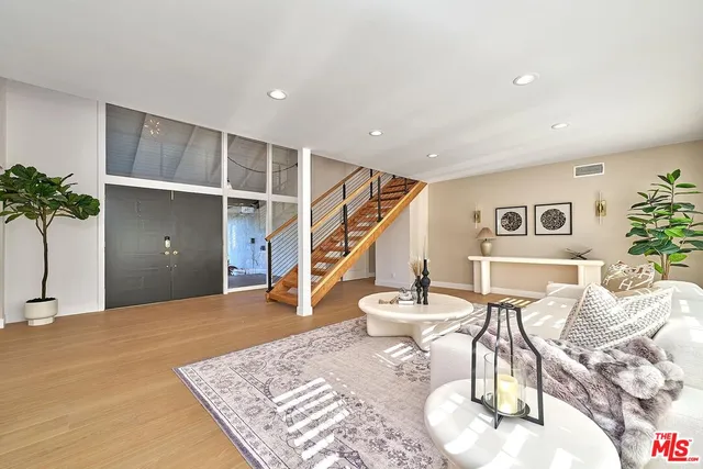 a view of a patio with couches table and chairs under an umbrella with potted plants