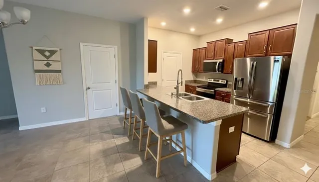a kitchen that has a kitchen island wooden cabinets and stainless steel appliances