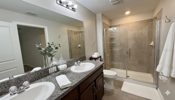 a bathroom with a granite countertop sink toilet a mirror a shower and a tub