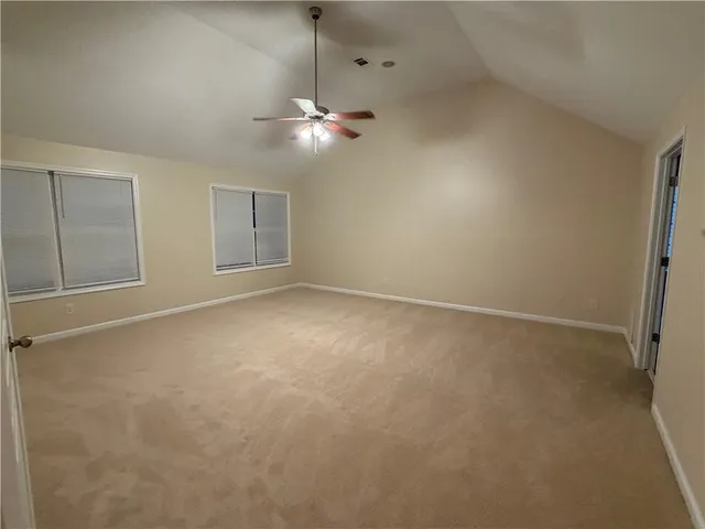 an empty room with chandelier fan and windows
