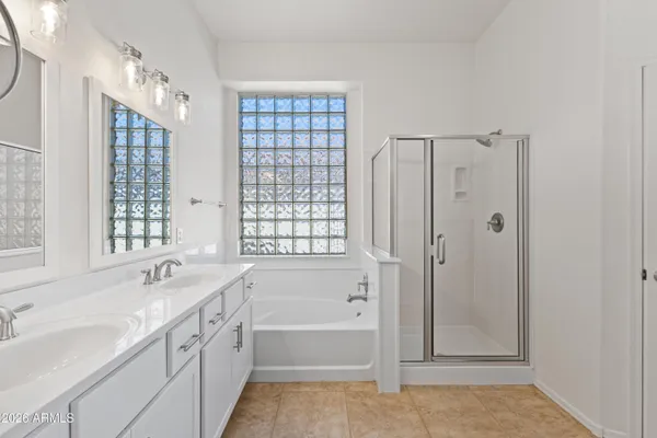 a bathroom with a tub sink double vanity and a shower