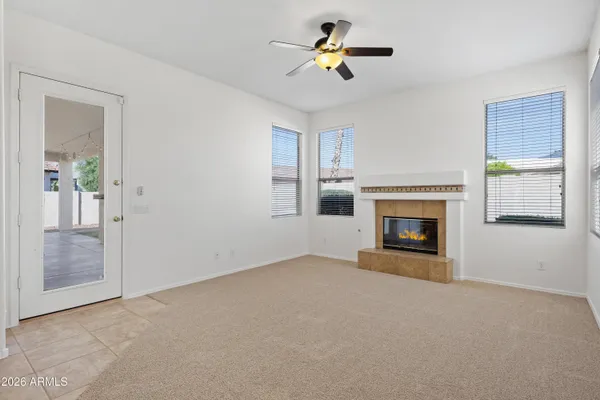 an empty room with a fireplace and a ceiling fan
