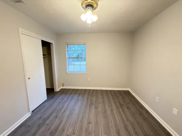 an empty room with a hardwood and windows