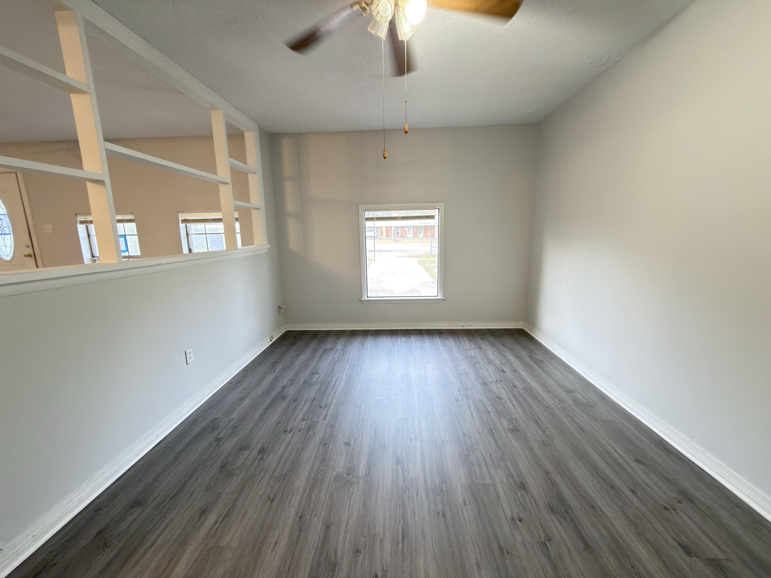 208 Forrest Parkway Crestview, FL 32539 - Photo 4 of 17 an empty room with wooden floor chandelier fan and windows