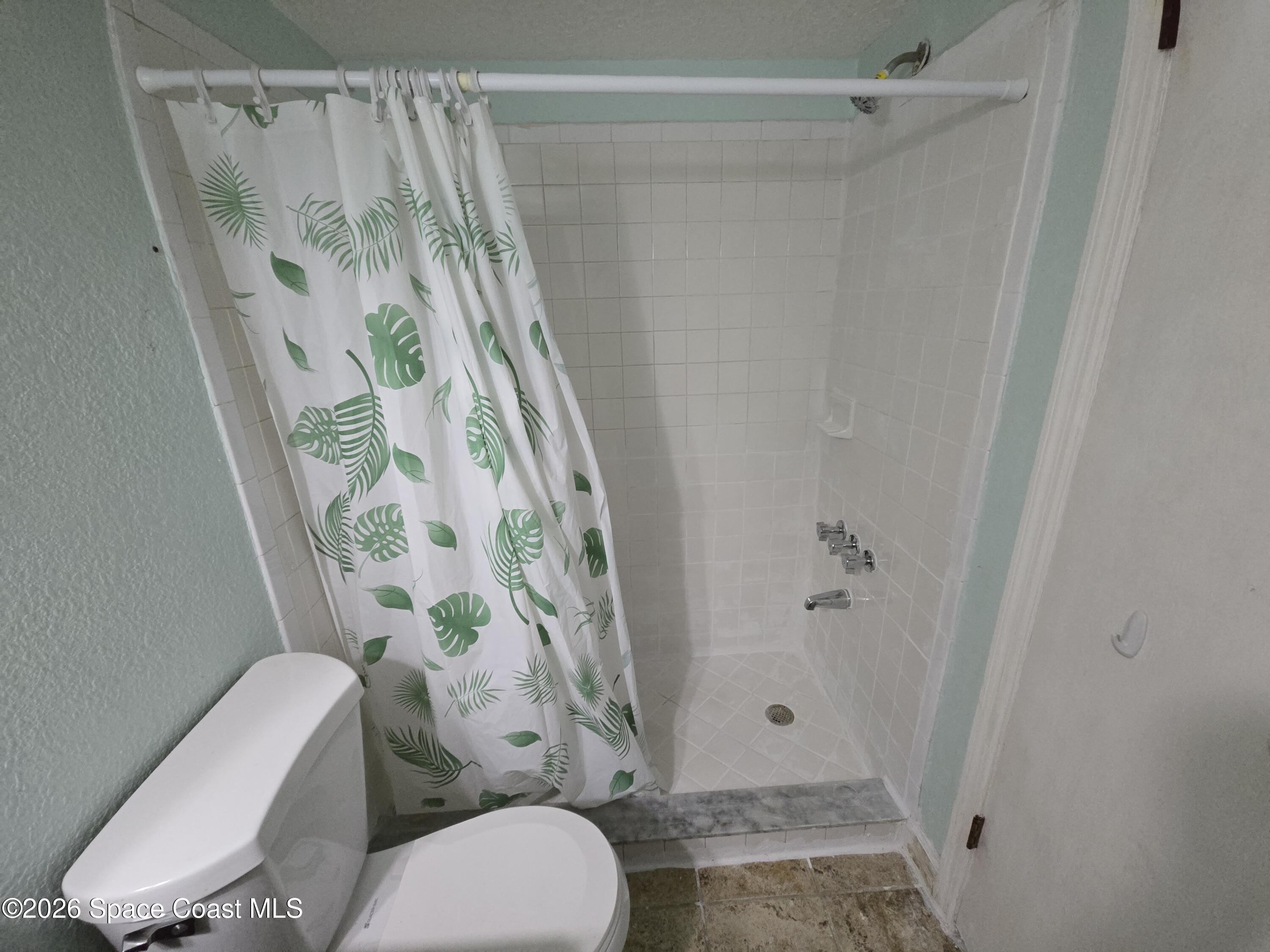174 Ulster Lane Melbourne, FL 32935 - Photo 16 of 25 a bathroom with a toilet and shower curtain