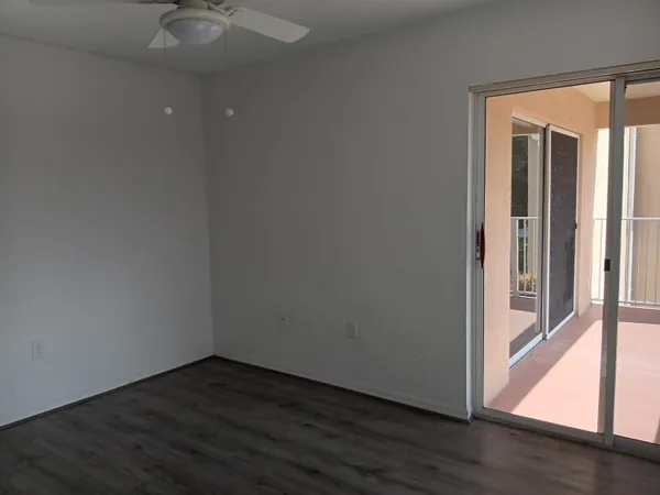 a view of an empty room with wooden floor and door