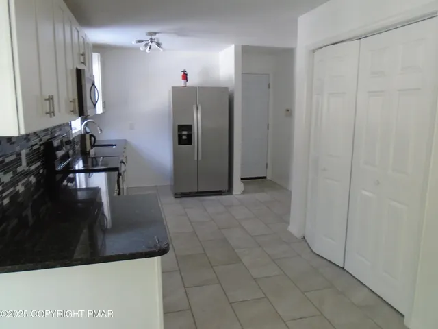a kitchen with granite countertop white cabinets and window