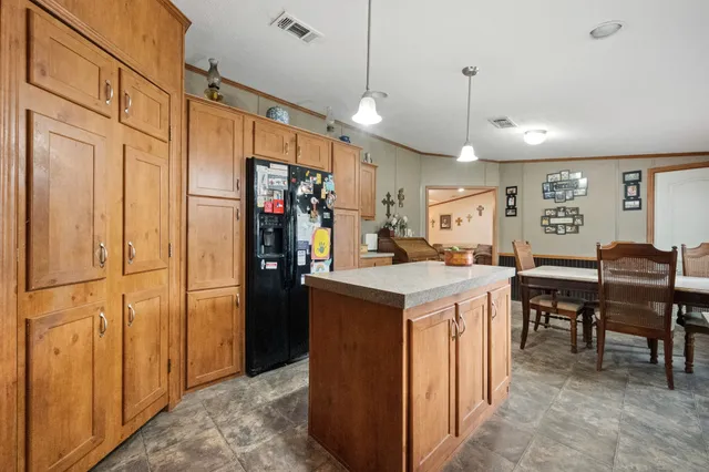 a kitchen with kitchen island a stove a refrigerator a dining table and chairs with wooden floor