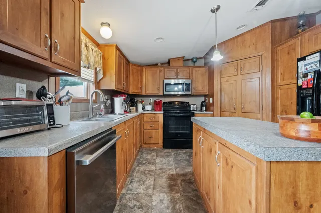 a kitchen with stainless steel appliances granite countertop a sink a stove and a wooden floors