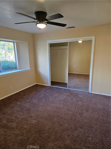 a view of an empty room with window and chandelier fan