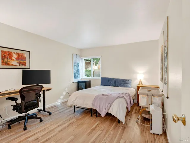 a bedroom with a bed a desk and chair with wooden floor