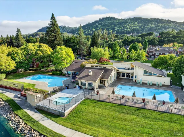 an aerial view of a house with swimming pool garden and mountain view in back