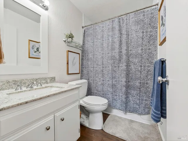 a bathroom with a granite countertop sink a toilet and a mirror