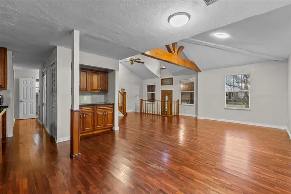 a kitchen with stainless steel appliances granite countertop white cabinets a refrigerator a stove a sink and dishwasher with wooden floor