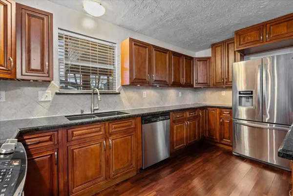 a kitchen with stainless steel appliances granite countertop wooden floor sink stove and granite counter top