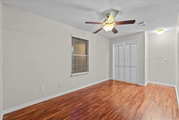 a view of an empty room with wooden floor and a window