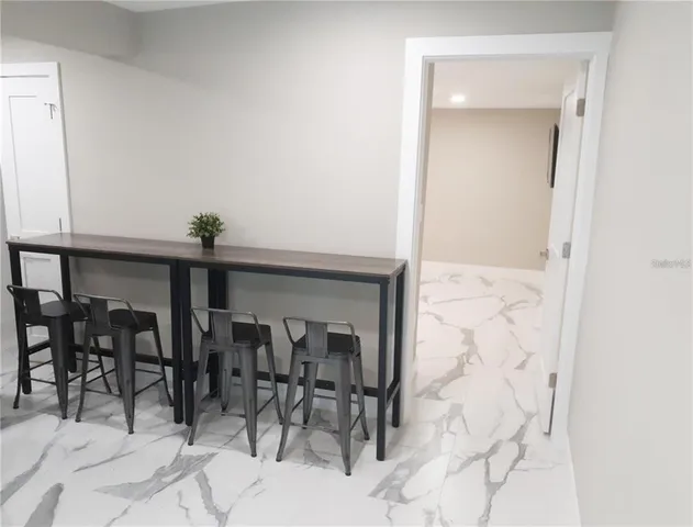 a kitchen with stainless steel appliances a table chairs refrigerator and microwave