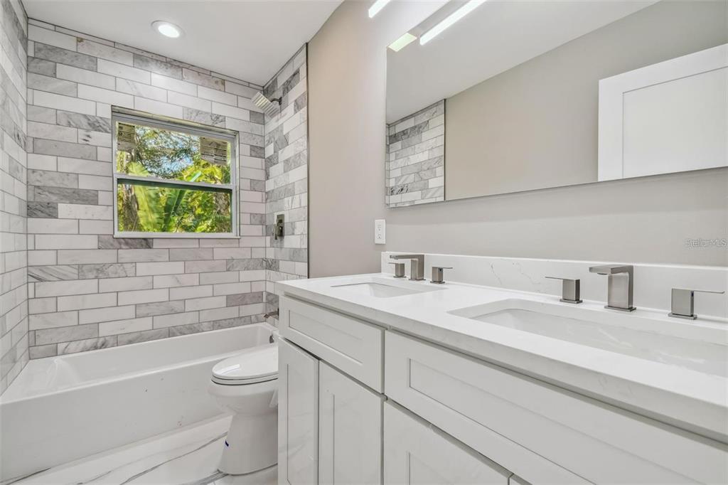 2042 Craft Lane Sarasota, FL 34239 - Photo 25 of 100 a bathroom with a granite countertop sink toilet a mirror and bathtub