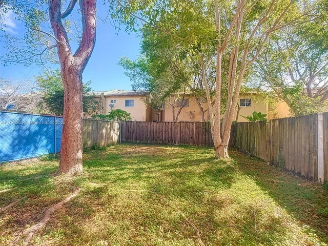 a backyard of a house with a large tree and wooden fence