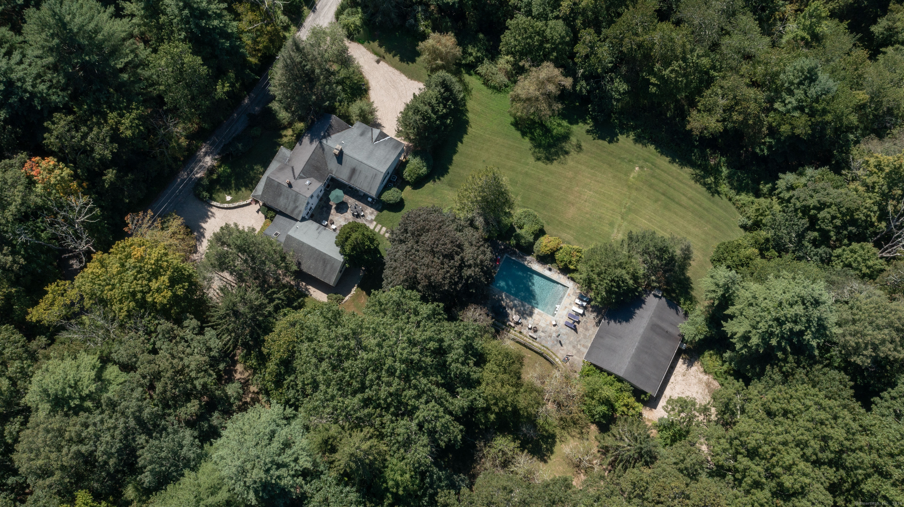 an aerial view of residential house with outdoor space and trees all around