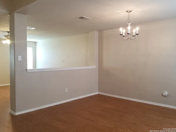 a view of an empty room with chandelier fan