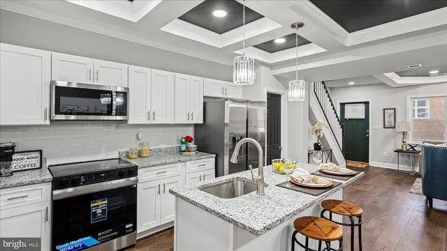 a kitchen with stainless steel appliances granite countertop a sink dishwasher stove refrigerator and cabinets with wooden floor