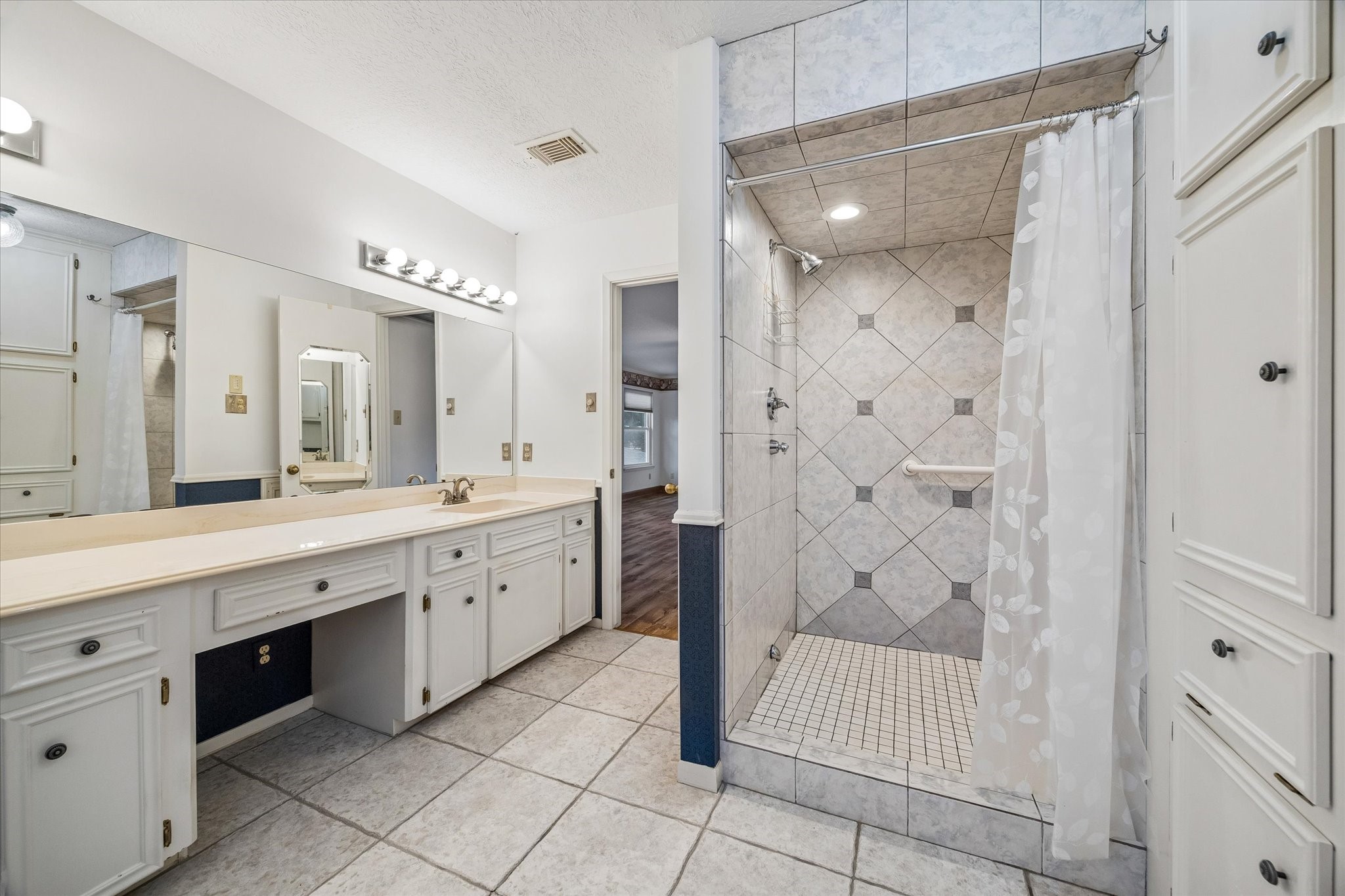 5515 Sylmar Road Houston, TX 77081 - Photo 14 of 28 The en-suite bath of the primary bedroom features a walk-in shower with multiple shower heads. The cabinets in this room offer a lot of storage.