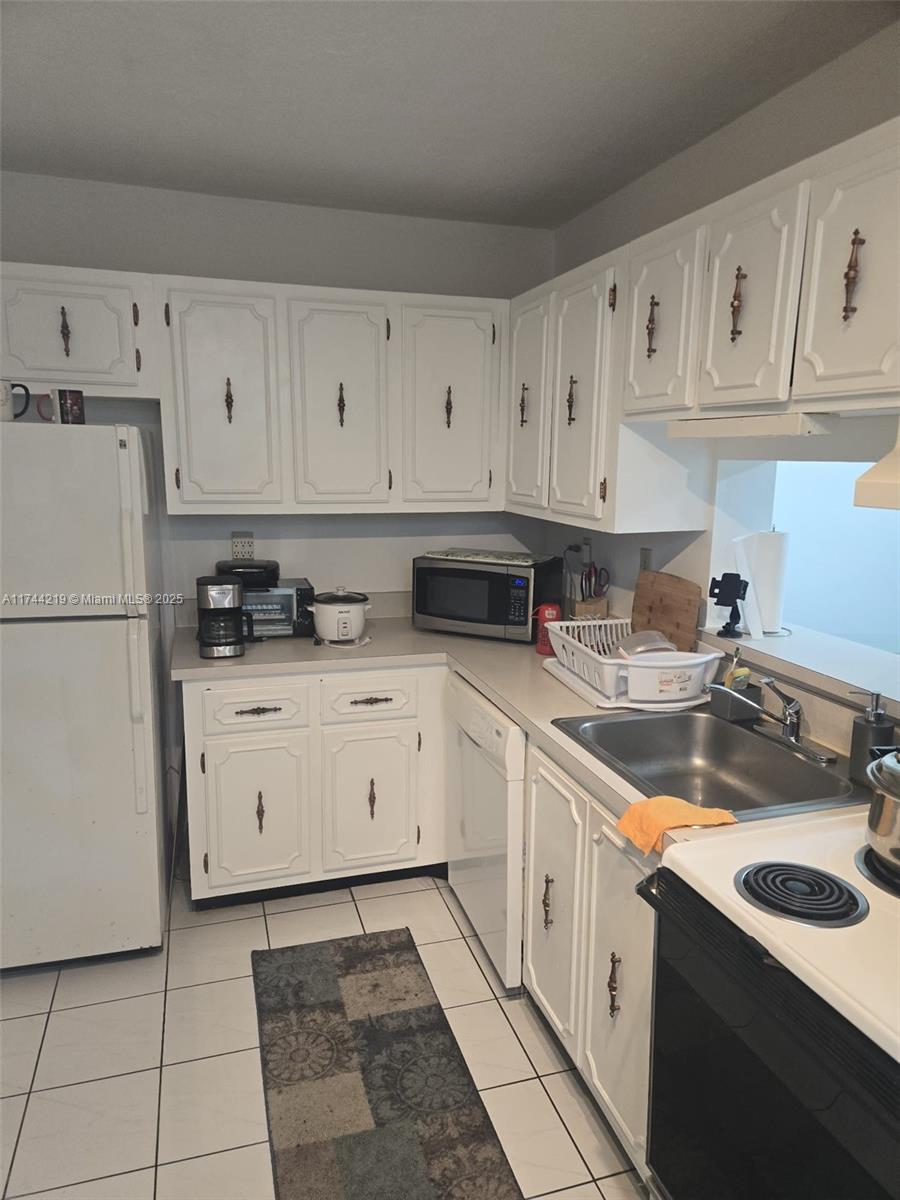 5201 Northwest 7th Street, Unit 403 Miami, FL 33126 - Photo 1 of 5 a kitchen with granite countertop a sink a stove a refrigerator and white cabinets