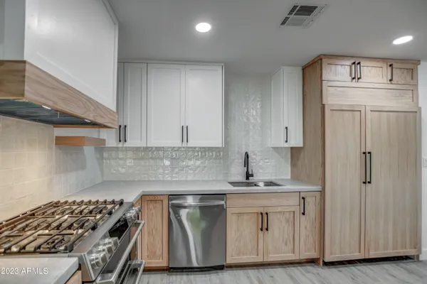 a kitchen with kitchen island granite countertop a sink cabinets and stainless steel appliances