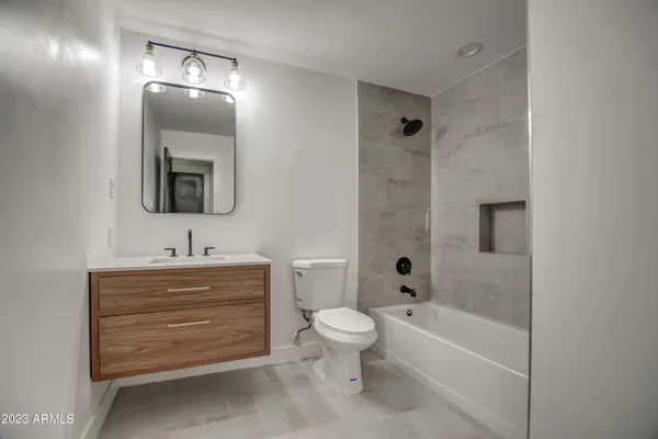 a bathroom with a toilet a sink a tub and mirror