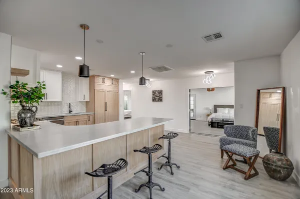 a kitchen with stainless steel appliances kitchen island granite countertop a stove a sink a refrigerator and white cabinets with wooden floor