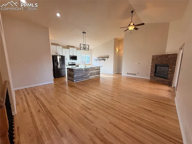 a view of empty room with a fireplace and wooden floor