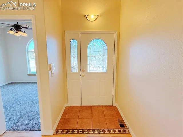 an empty room with a chandelier fan and windows