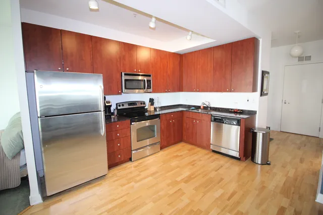 a kitchen with stainless steel appliances granite countertop a refrigerator a sink and a stove